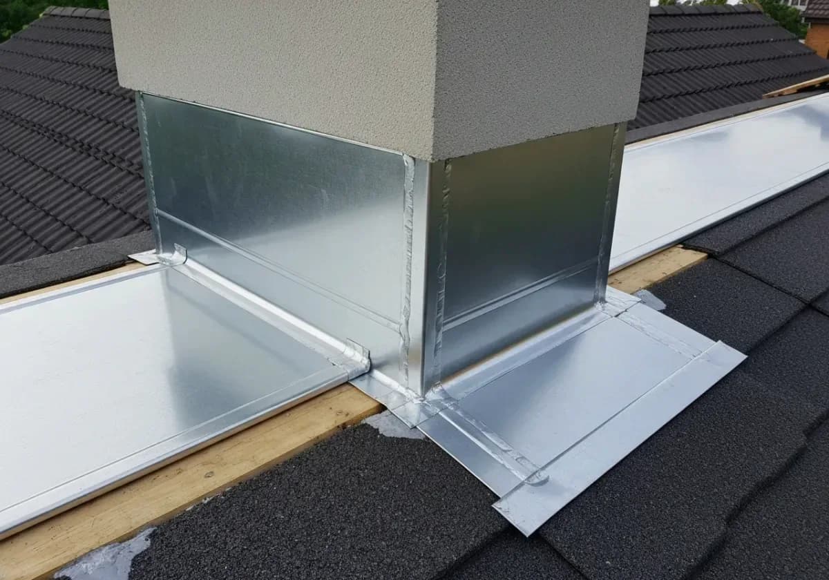 After — chimney flashing repair: Corroded, weeping flashing stripped and resealed at the roof-to-chimney joint.