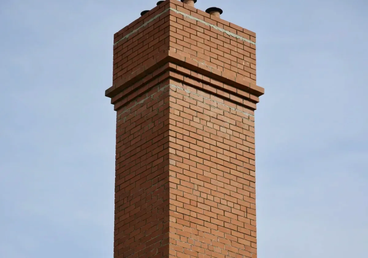 After — chimney repair: Flaking brick and washed-out mortar rebuilt into a stack that sheds weather again.